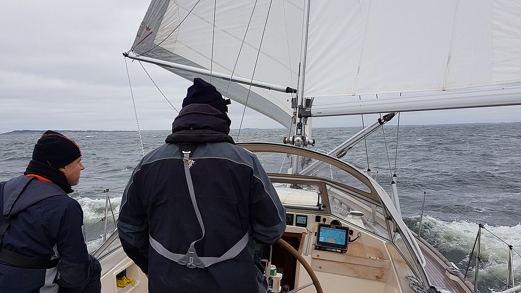 Foto af to mænd bag roret på et sejlskib